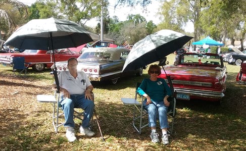 People with classic cars and umbrellas