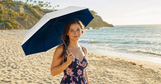 Person on sunny beach holding UV-Blocker compact umbrella with silver reflective canopy for beach umbrella size guide