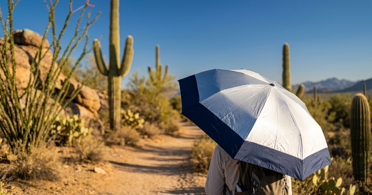 Person walking on Arizona desert trail with UV-Blocker silver sun protection umbrella among saguaro cacti